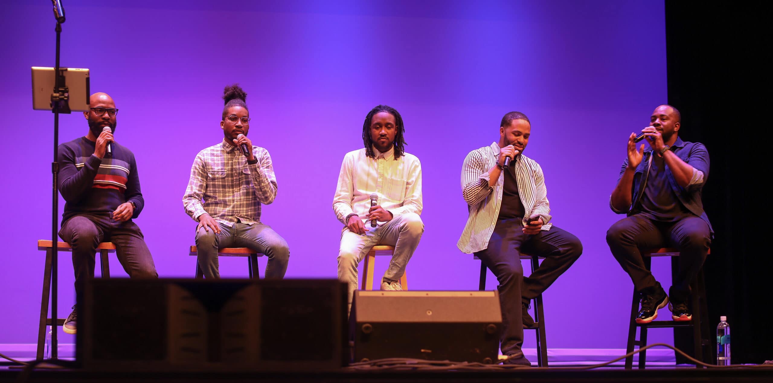 5 men sitting on stools while singing. Members of Committed (left to right): Maurice Staple, Brent Hoyle, Theron “Therry” Thomas, Robbie Pressley, and Dennis “DJ” Baptiste Jr.