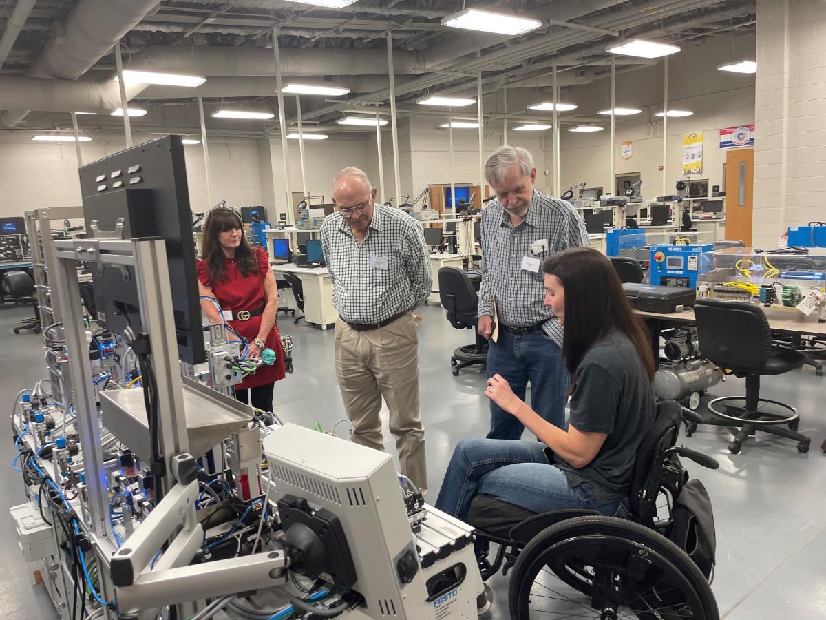 Thomas Carr, Julie Pierce, and Bill Sanford listen to Electronics Technology Instructor Sam McNease explain equipment used in training students.