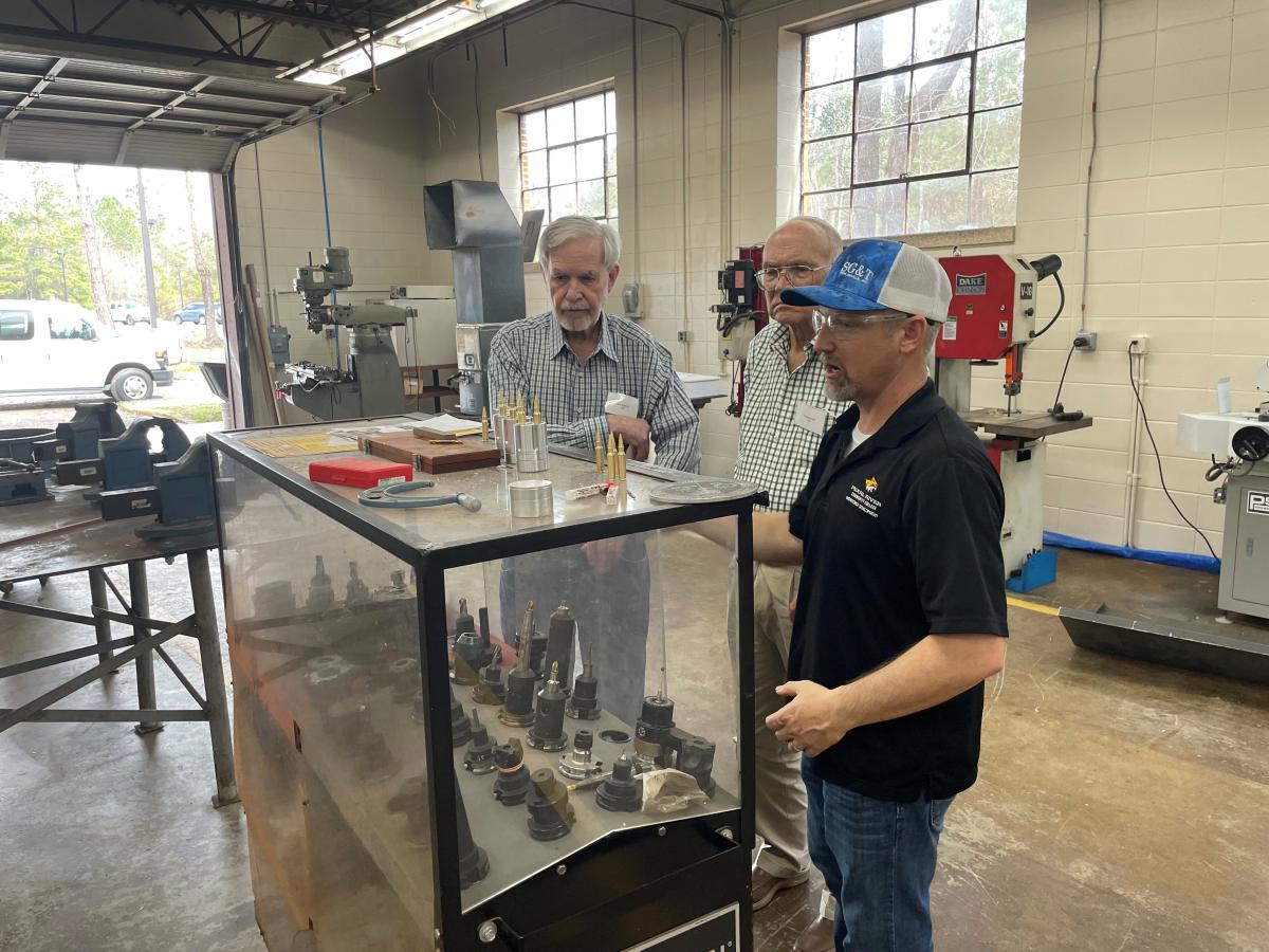 Thomas Carr and Bill Sanford view different equipment used by Precision Manufacturing Technology while instructor Robert Shaw describes what they do. 