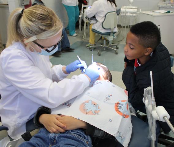 Seven-year-old Nicholas Keys keeps a check on what Pearl River Community College dental hygiene student Chelsea Ford is doing to his friend, Alec McKenzie, during Give Kids A Smile Day at PRCC. The boys attend Grace Christian Elementary School in Hattiesburg.