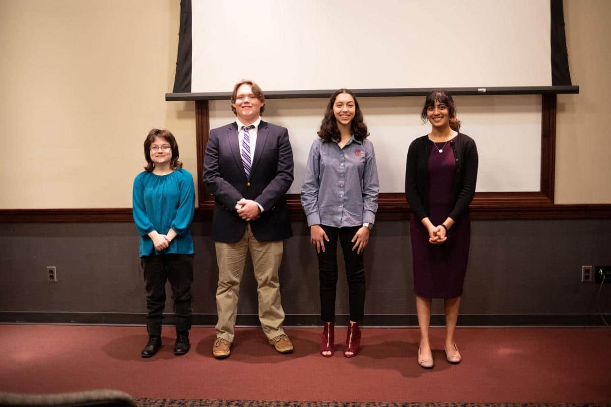 Woman with blue shirt, man in suit with striped tie, girl with grey shirt, girl with purple shirt and black sweater