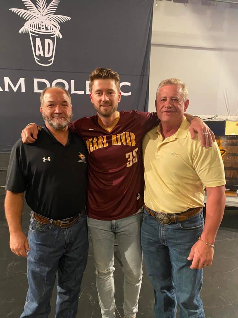 Adam Doleac wears PRCC jersey sporting the number 35 while his arms rest on Bryan Maxie on the left and his father on the right.