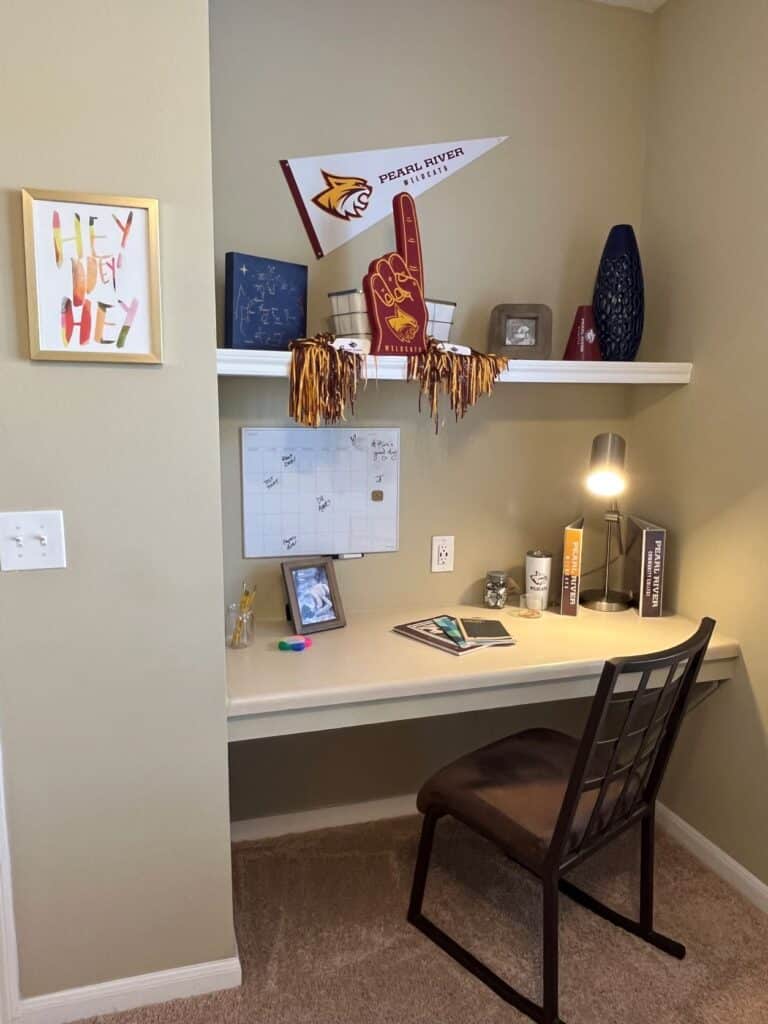 Built in desk with chair. Calendar on wall with assorted Pearl River Community College items on the desk and shelf.