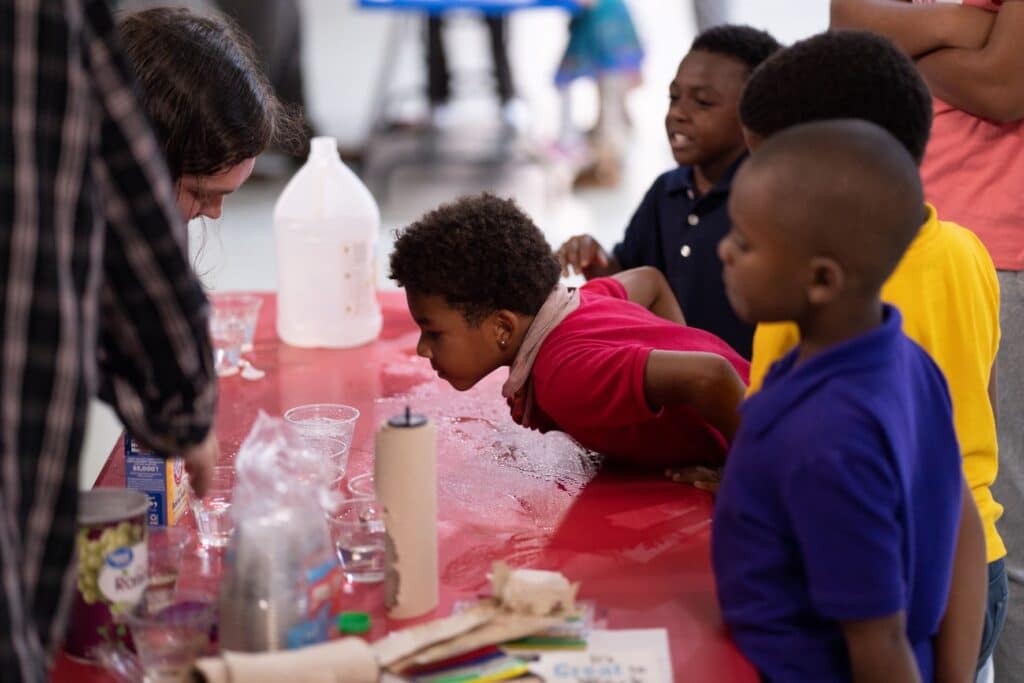 Boy looks closely at STEAM activity with PRCC students.