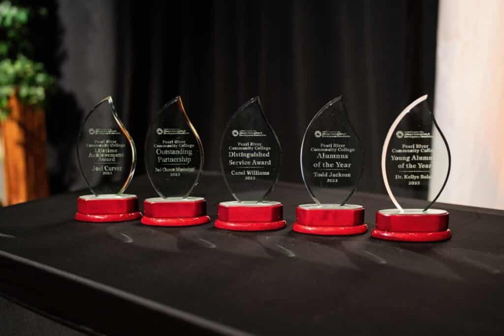 5 tear shaped awards stand on table with black tablecloth.