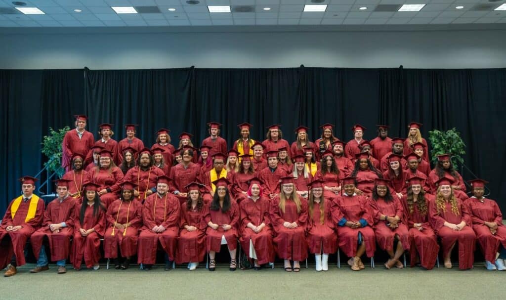 Four rows of graduates in maroon gowns.