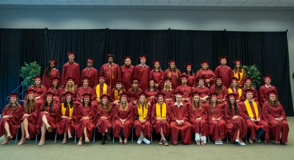 Three rows of men and women wearing maroon graduation gowns