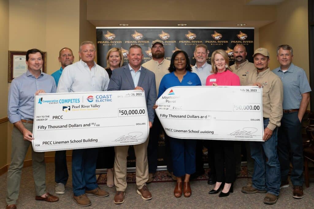 Group of men and women holding large checks stand in two rows.