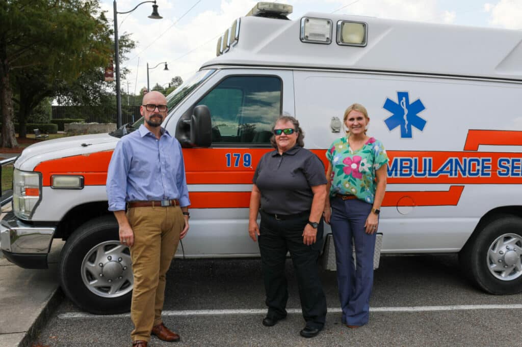 Man and two women tnd next to ambulance.