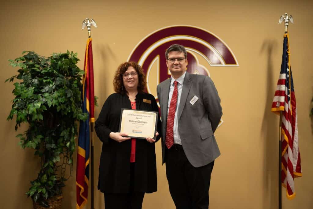 Woman holds certificate while standing next to man.