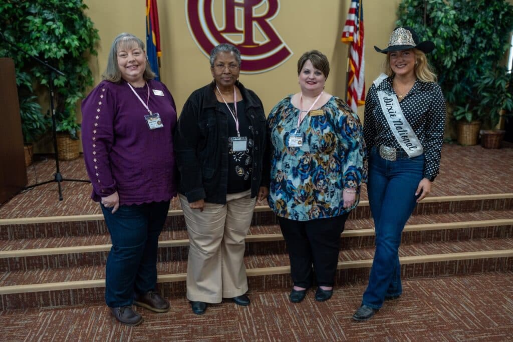 Four women stand in line with PRCC emblem on wall behind them.